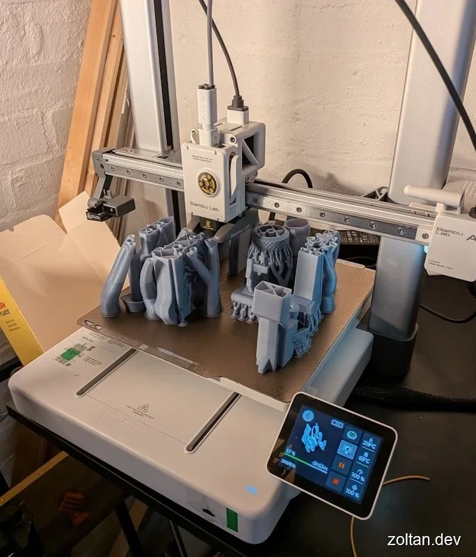 A Bambu Lab A1 3D printer in action, displaying several 3D printed objects.
