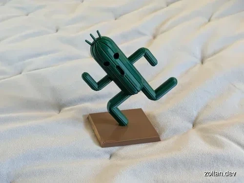 A green Cactuar figurine with a surprised expression stands on a brown base against a white textured background.