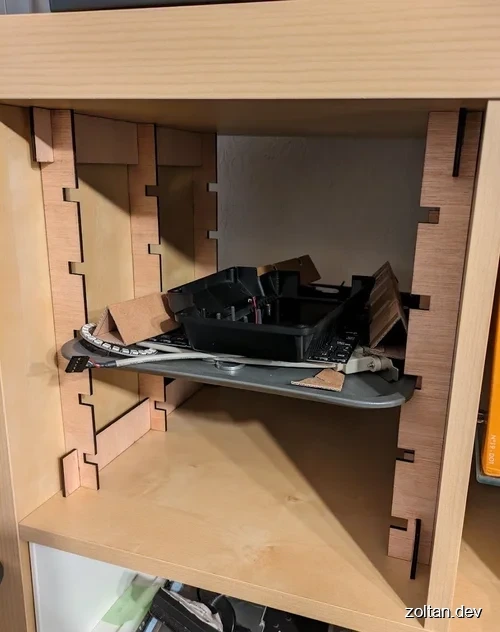 An open wooden cabinet shelf with laser-cut shelf holders.