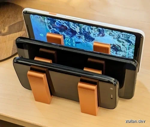 Three smartphones stacked vertically in a holder made from copper PLA.