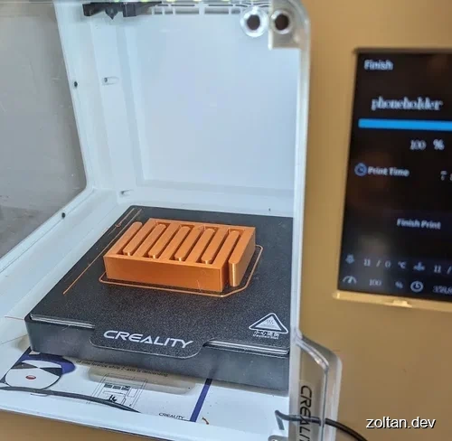 CREALITY 3D printer displaying a partially printed smartphone holder.