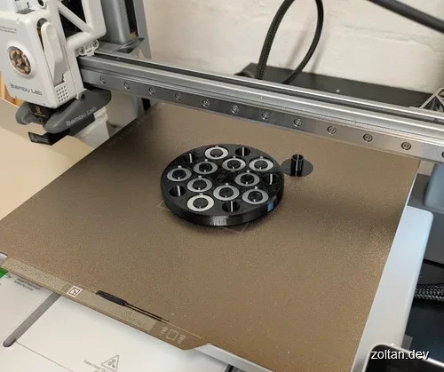 3D printed circular object with multiple holes and washers inserted into the holes.
