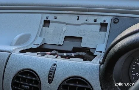 Close-up view of a car dashboard panel removed to reveal internal components and wiring.