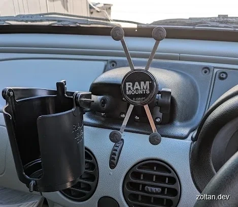 A vehicle dashboard with attached cup holder and X grip phone mount.